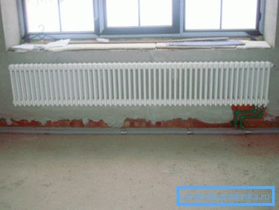 Under det brede vinduet ville en bred radiator være passende. Under det brede vinduet ville en bred radiator være passende.